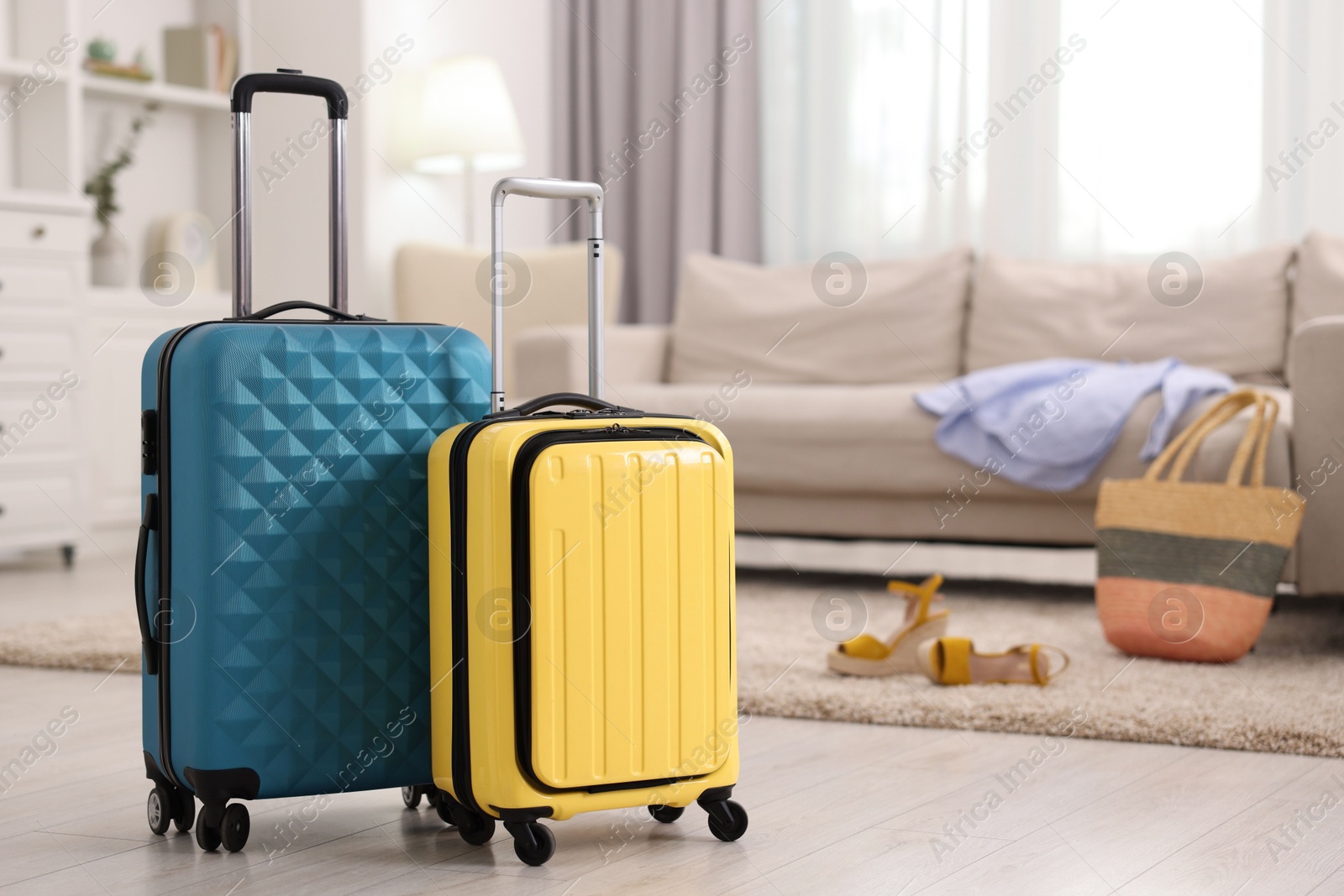 Photo of Two color suitcases on floor at home, space for text