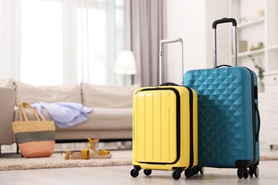 Photo of Two color suitcases on floor at home, space for text