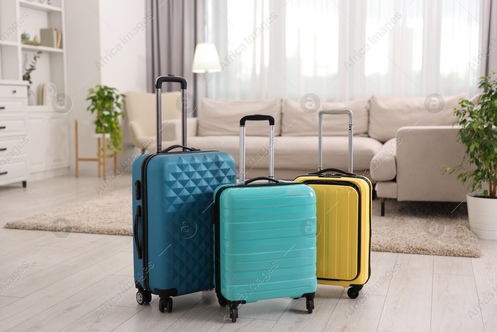 Photo of Three color suitcases on floor at home