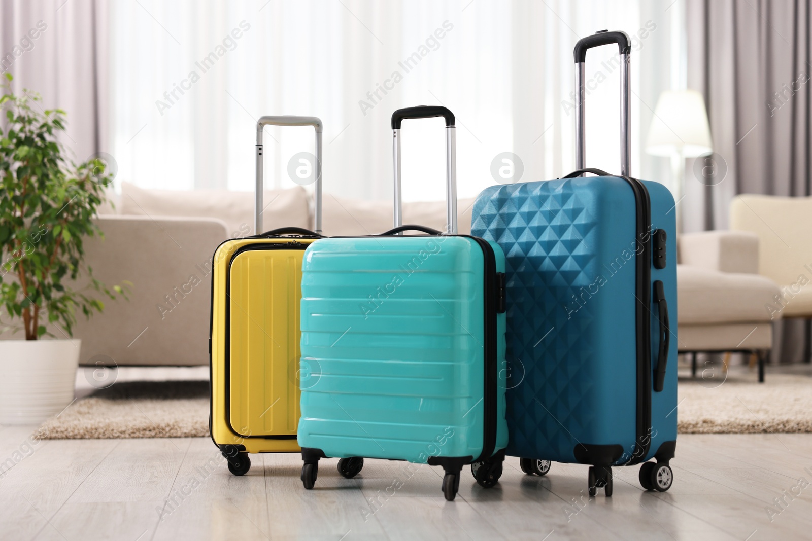 Photo of Three color suitcases on floor at home