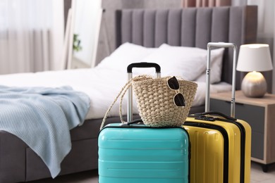 Photo of Color suitcases, bag and sunglasses in bedroom