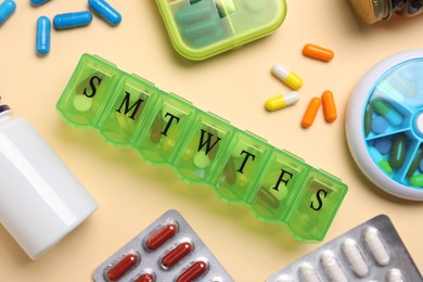 Photo of Different pills, organizers and medical jars on beige background, flat lay