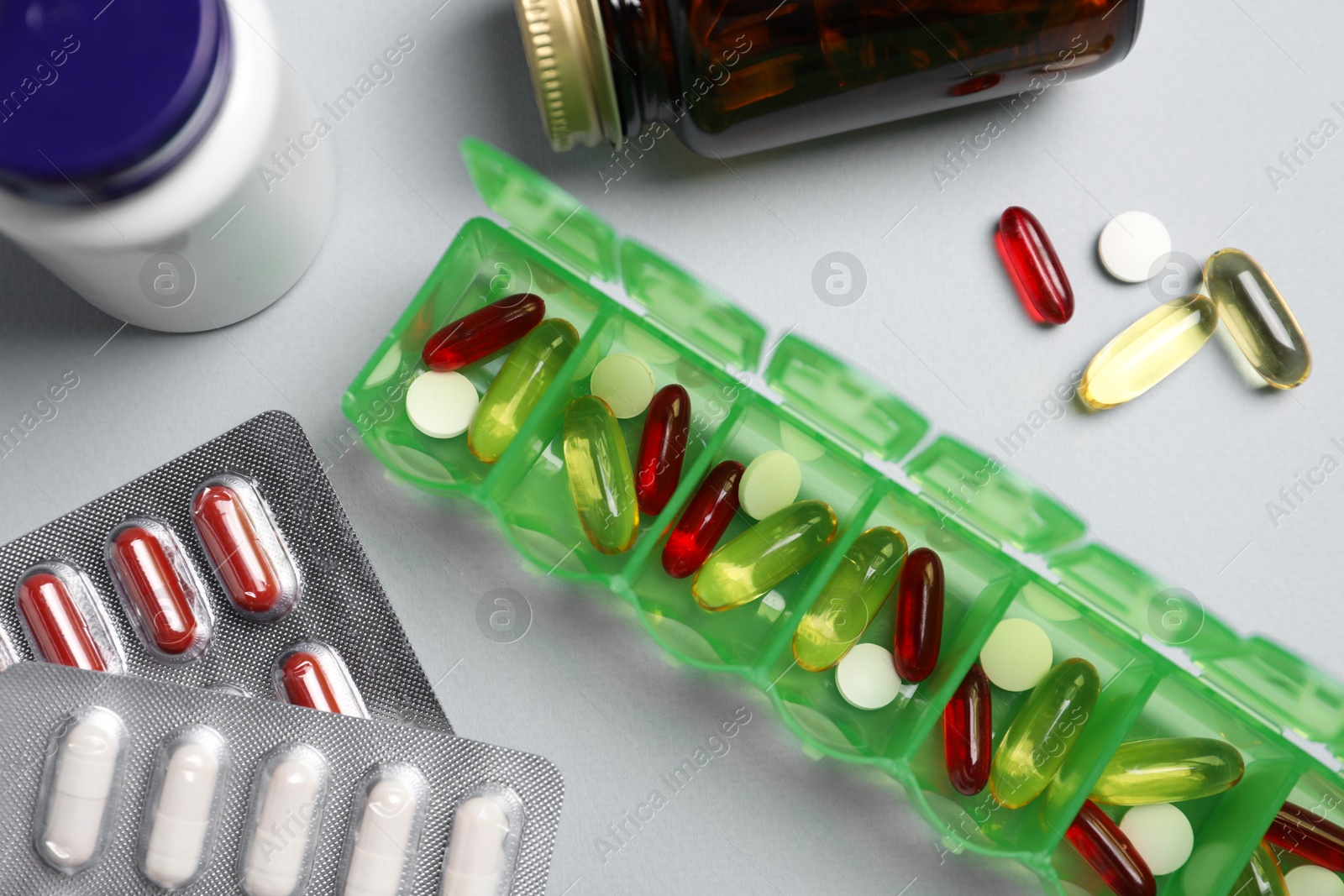 Photo of Different pills, organizer and medical jars on light background, flat lay