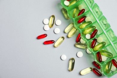 Photo of Different pills and organizer on light background, flat lay. Space for text