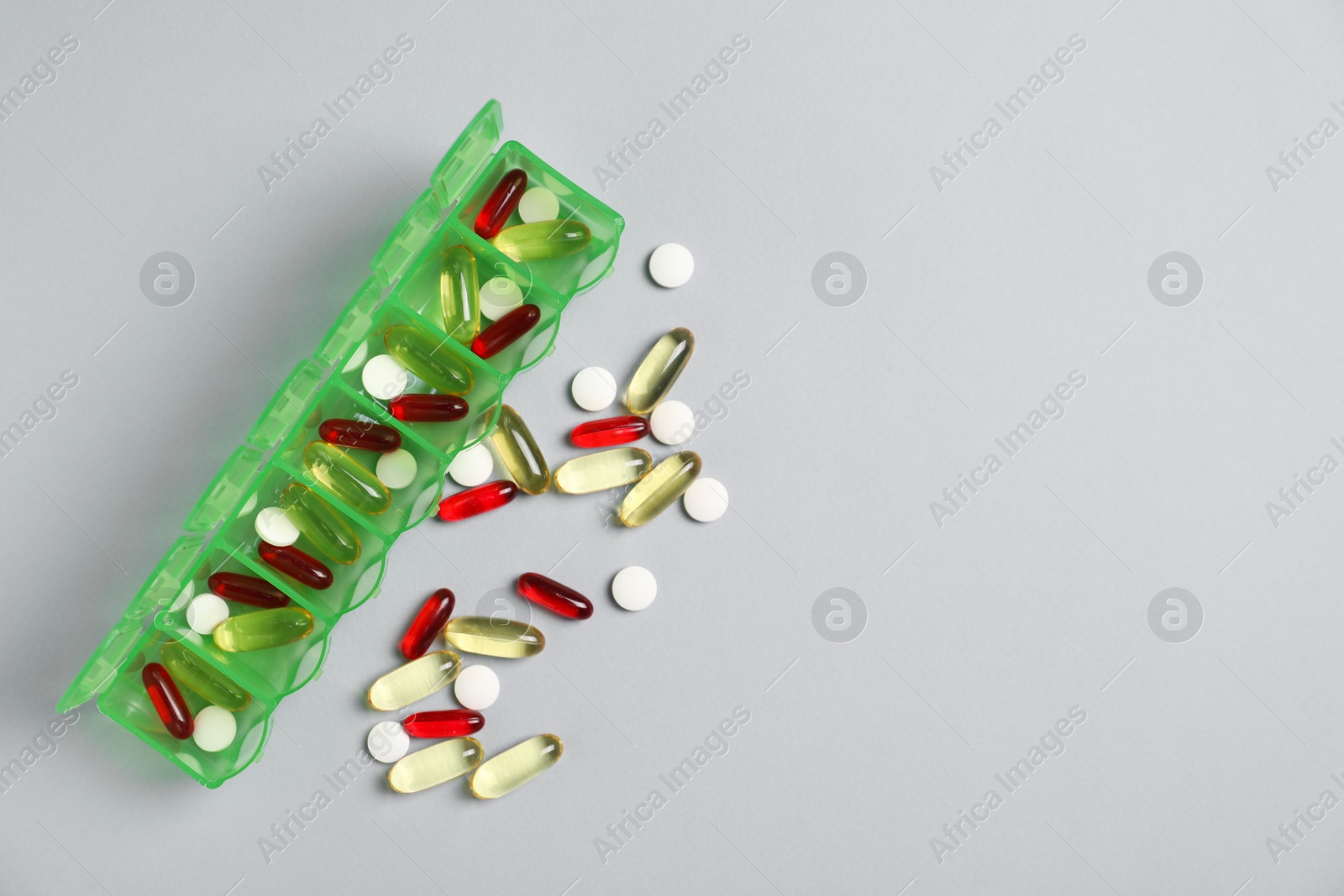 Photo of Different pills and organizer on light background, flat lay. Space for text