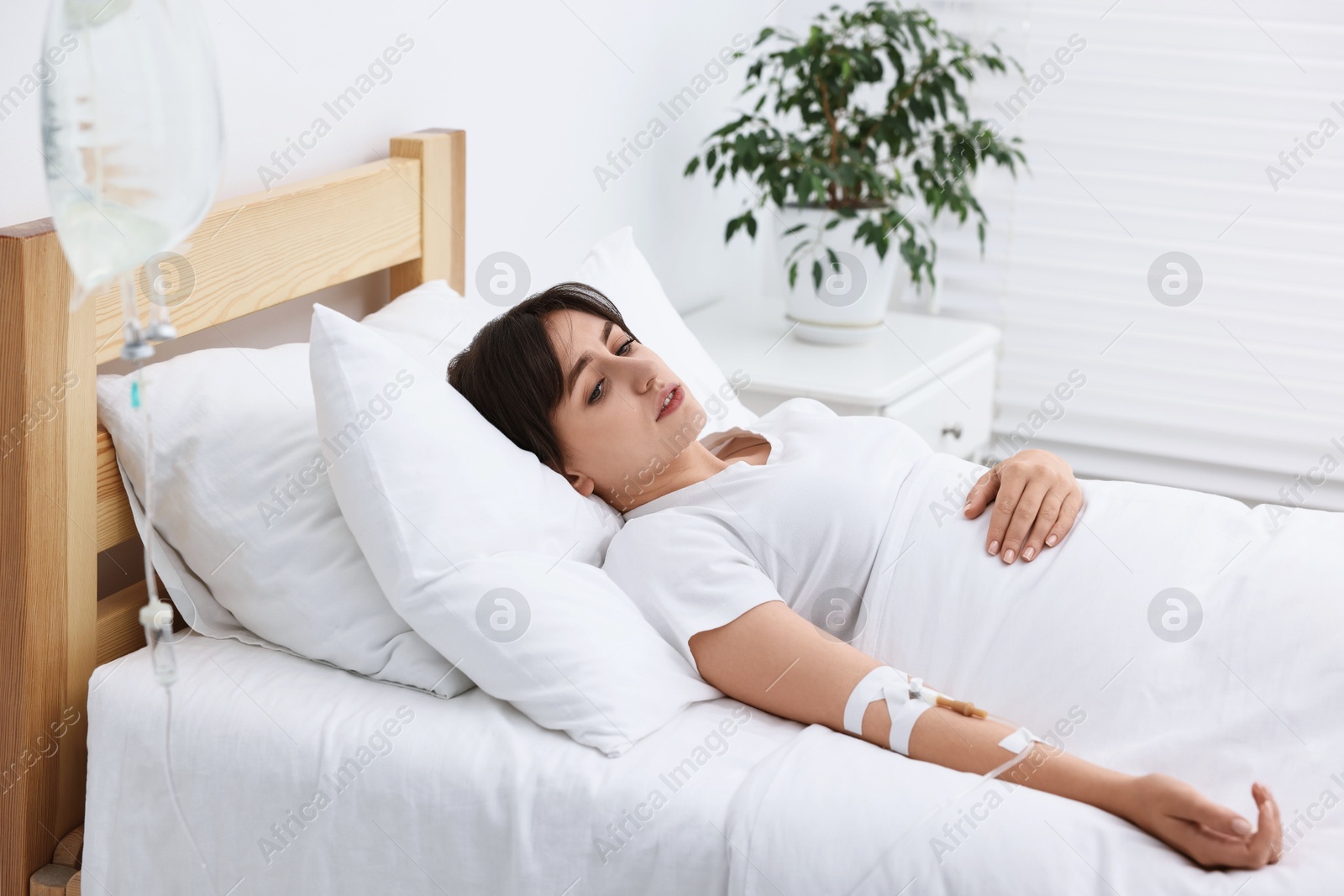 Photo of Young woman with intravenous drip in hospital bed