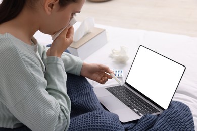 Photo of Sick woman with thermometer having online consultation with doctor via laptop at home