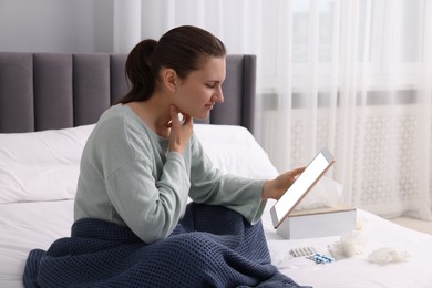 Sick woman having online consultation with doctor via tablet at home