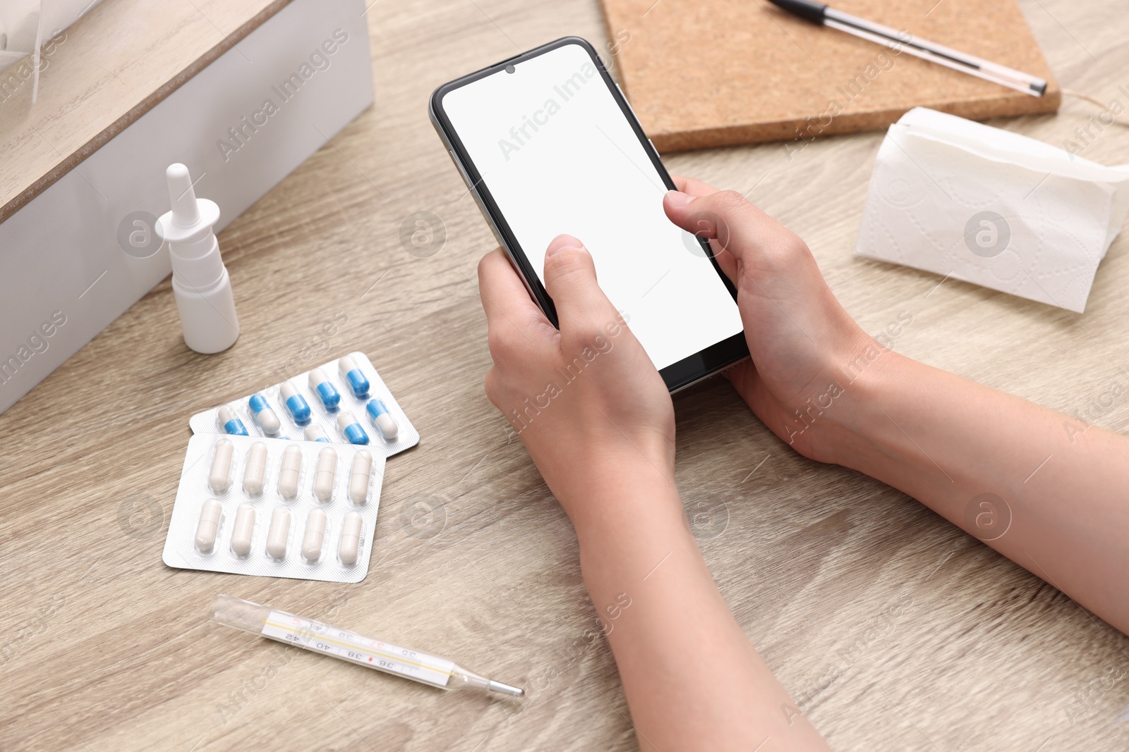 Photo of Sick woman having online consultation with doctor via smartphone at wooden table, closeup