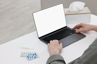 Sick man having online consultation with doctor via laptop at white table indoors, closeup