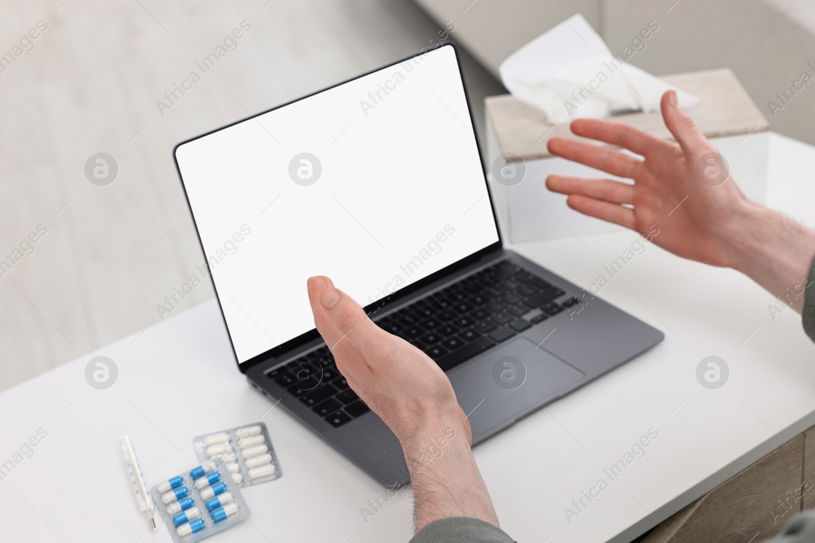 Photo of Sick man having online consultation with doctor via laptop at white table indoors, closeup