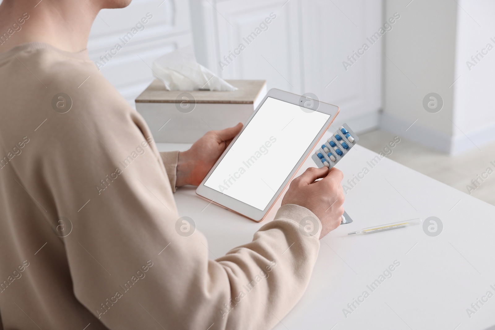 Photo of Sick man having online consultation with doctor via tablet at white table indoors, closeup