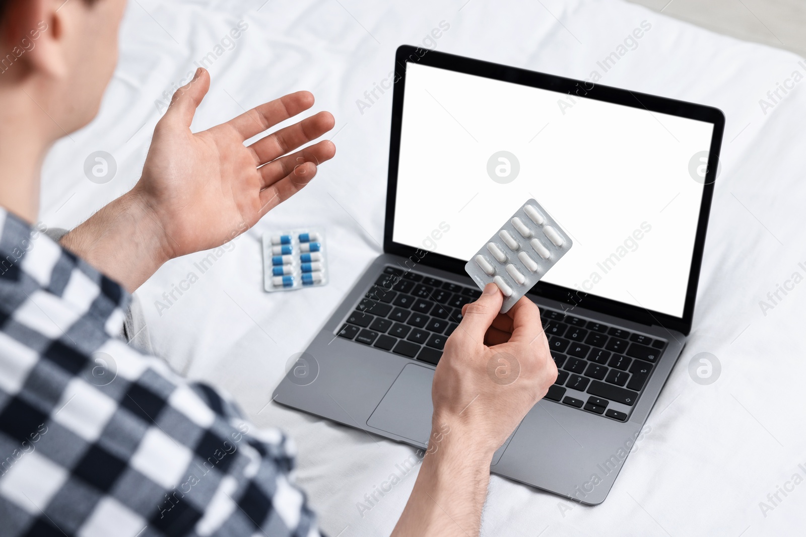 Photo of Sick man with pills having online consultation with doctor via laptop at home, closeup