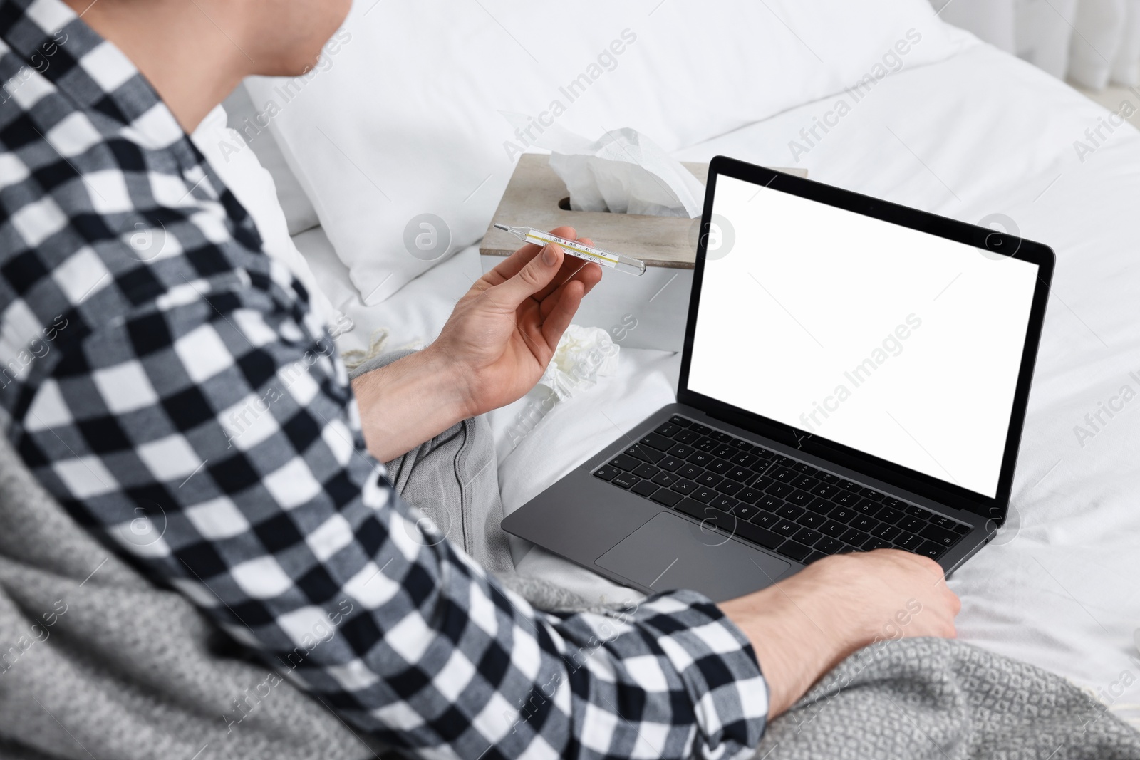 Photo of Sick man with thermometer having online consultation with doctor via laptop at home, closeup