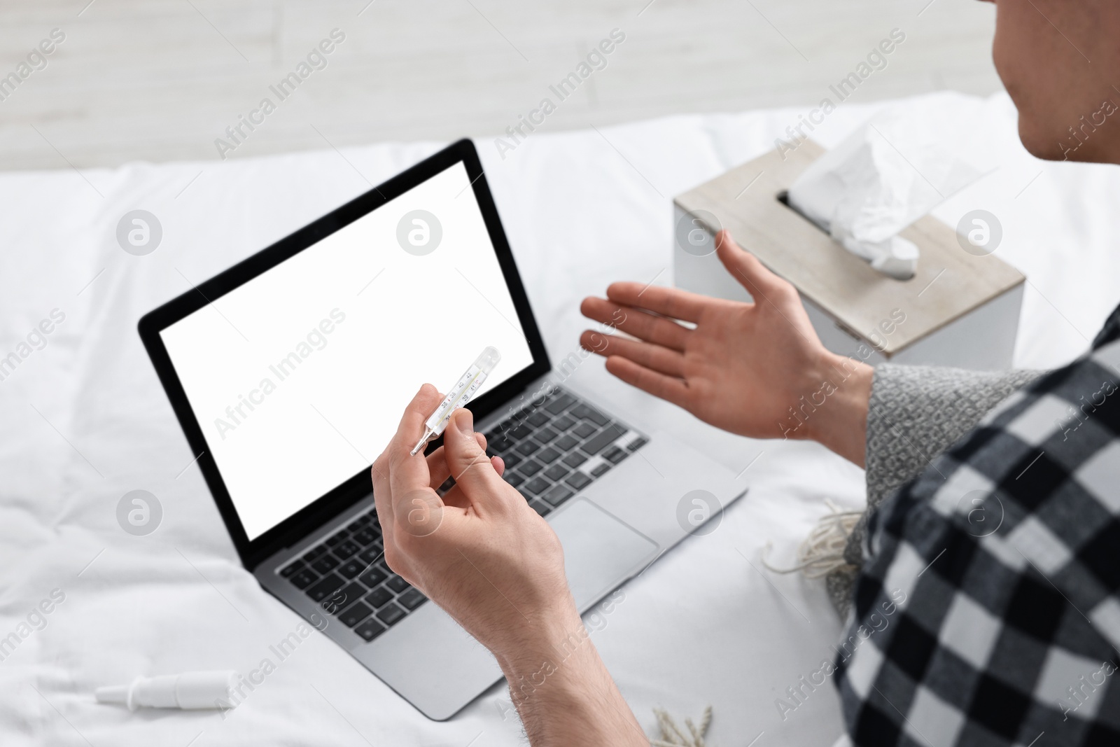 Photo of Sick man with thermometer having online consultation with doctor via laptop at home, closeup