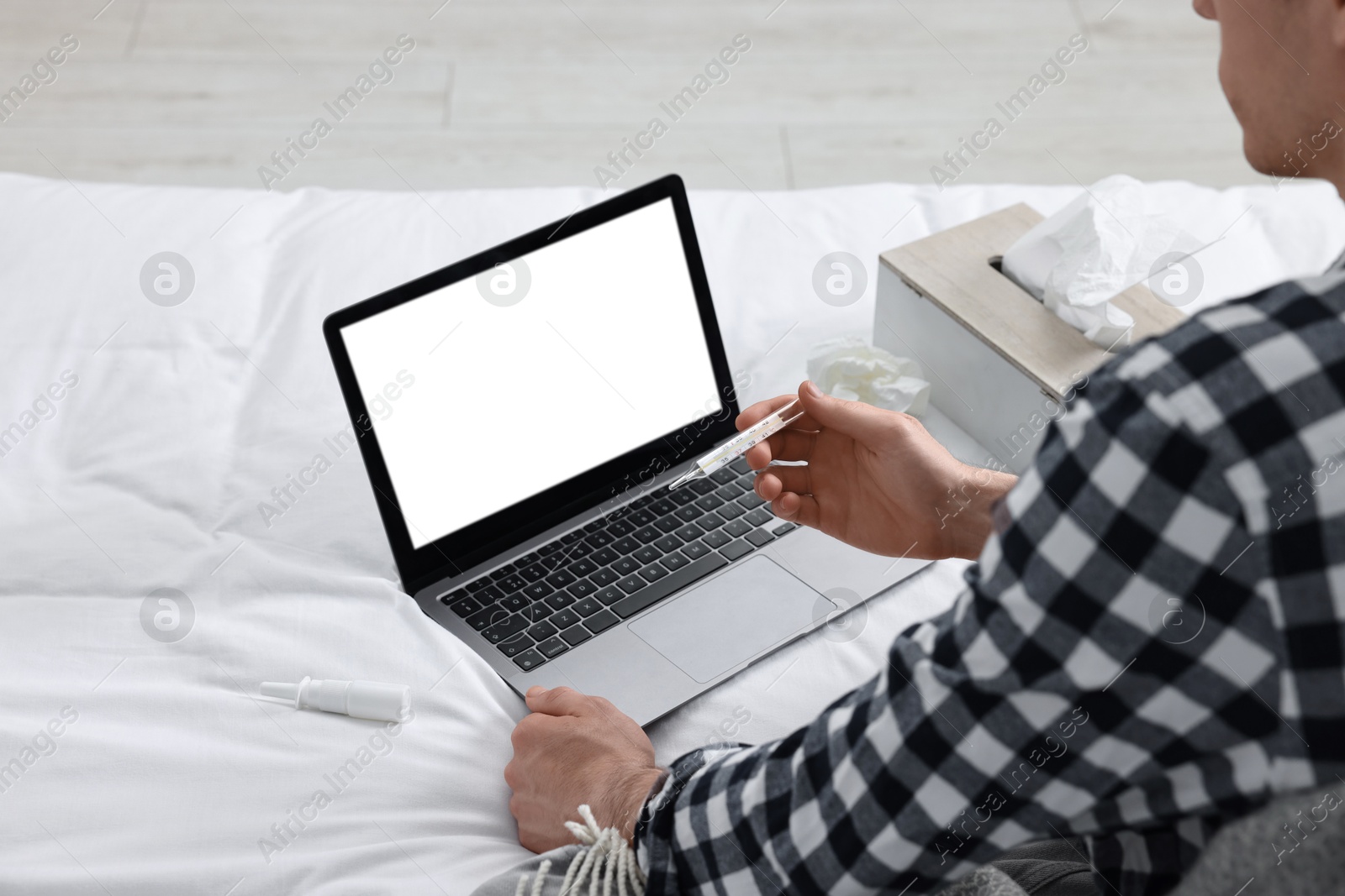 Photo of Sick man with thermometer having online consultation with doctor via laptop at home, closeup