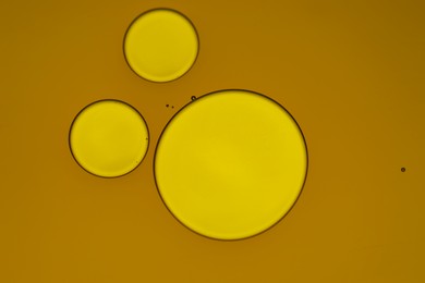 Photo of Sample of cosmetic oil on dark yellow background, macro view