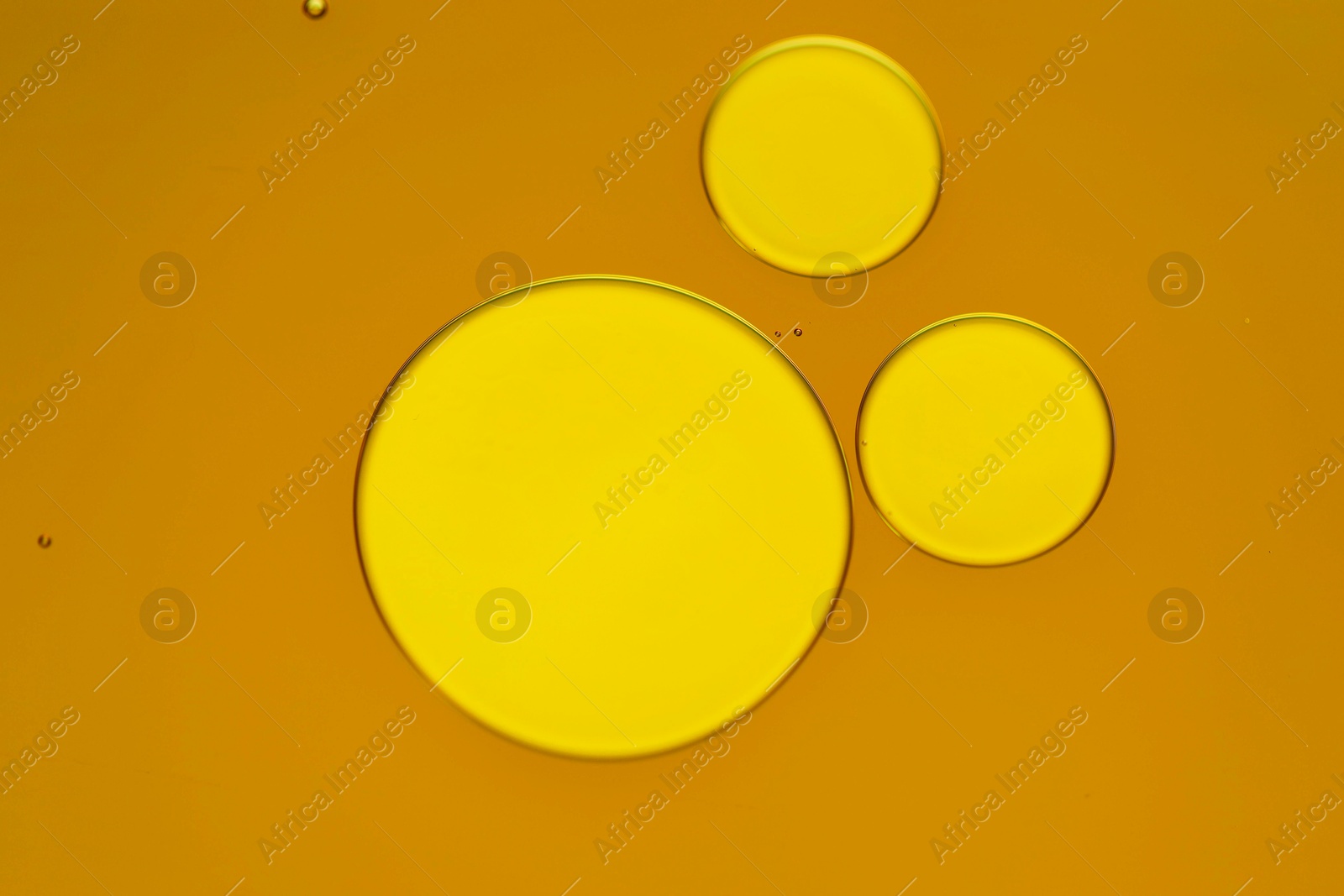 Photo of Sample of cosmetic oil on dark yellow background, macro view