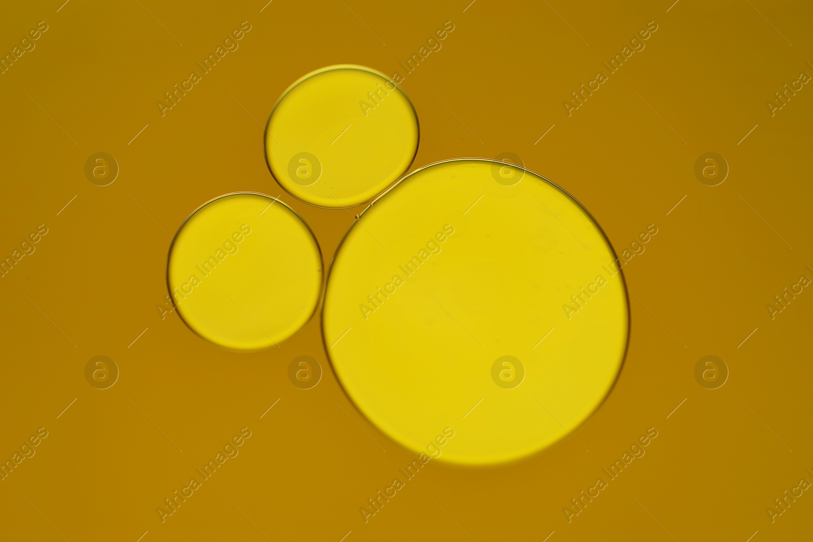 Photo of Sample of cosmetic oil on dark yellow background, macro view