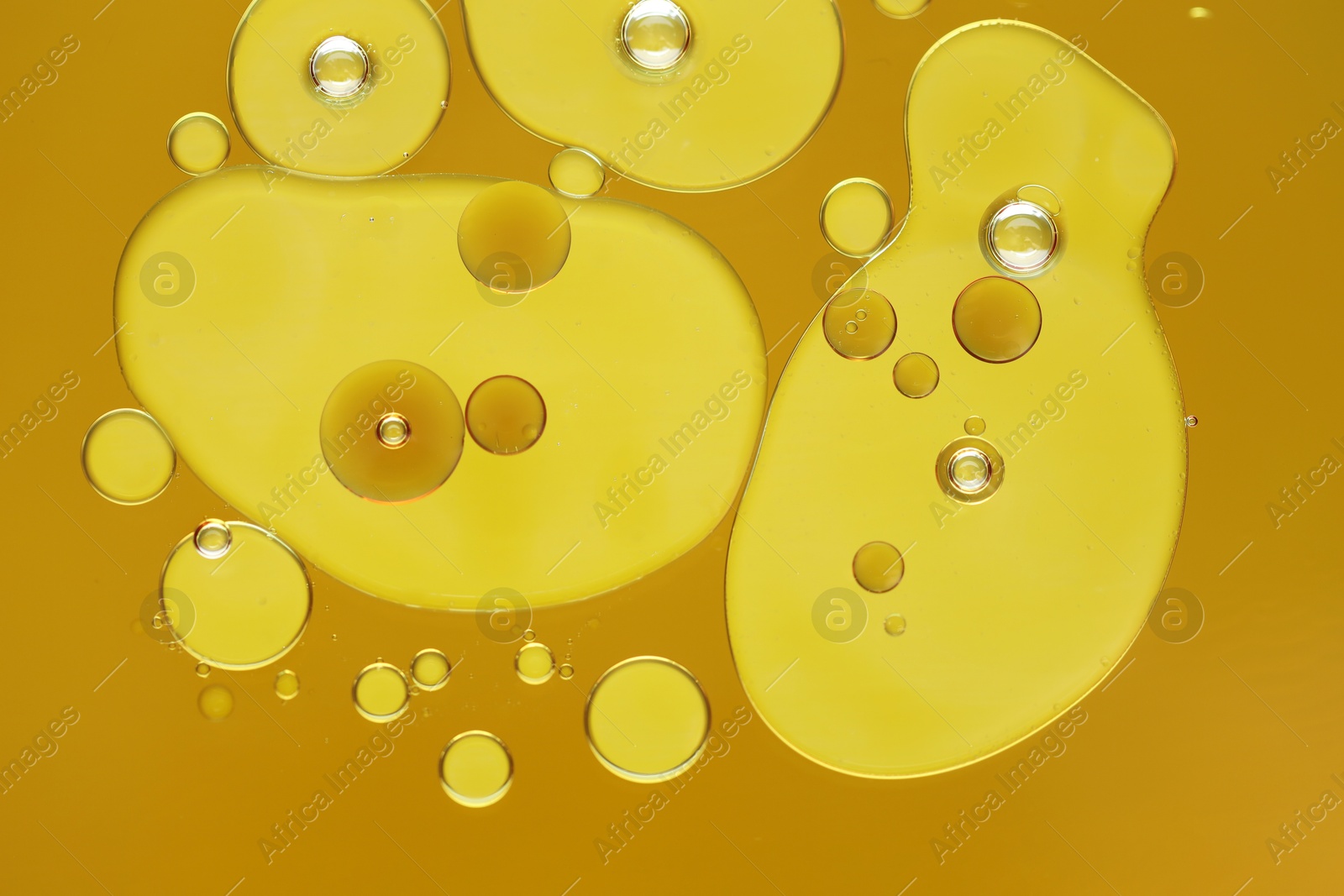 Photo of Sample of cosmetic oil on dark yellow background, macro view