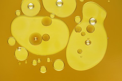 Photo of Sample of cosmetic oil on dark yellow background, macro view