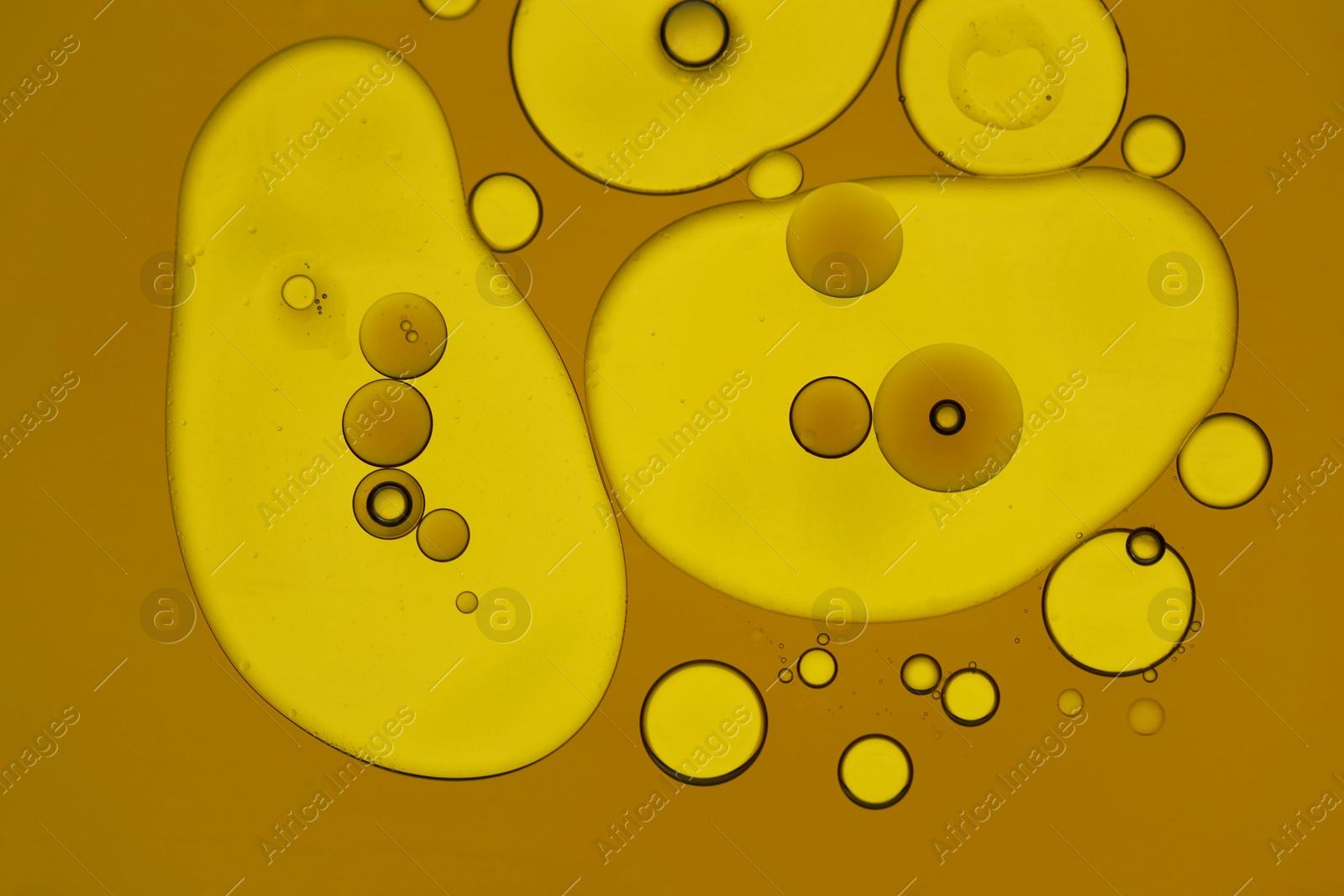 Photo of Sample of cosmetic oil on dark yellow background, macro view