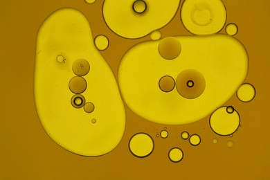 Photo of Sample of cosmetic oil on dark yellow background, macro view