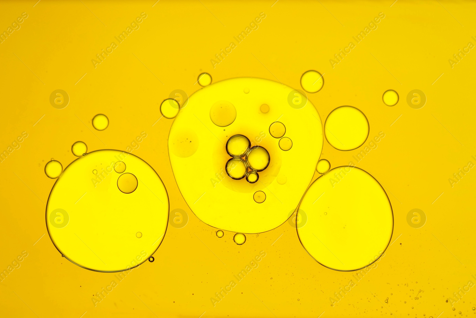 Photo of Sample of cosmetic oil on yellow background, macro view