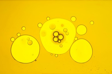 Photo of Sample of cosmetic oil on yellow background, macro view