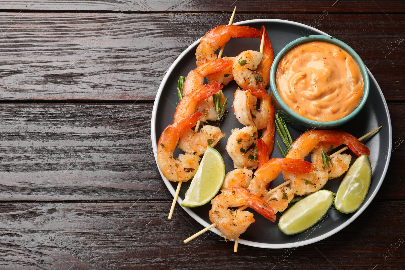 Photo of Skewers with delicious grilled shrimps served on wooden table, top view. Space for text