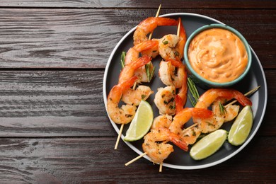 Photo of Skewers with delicious grilled shrimps served on wooden table, top view. Space for text