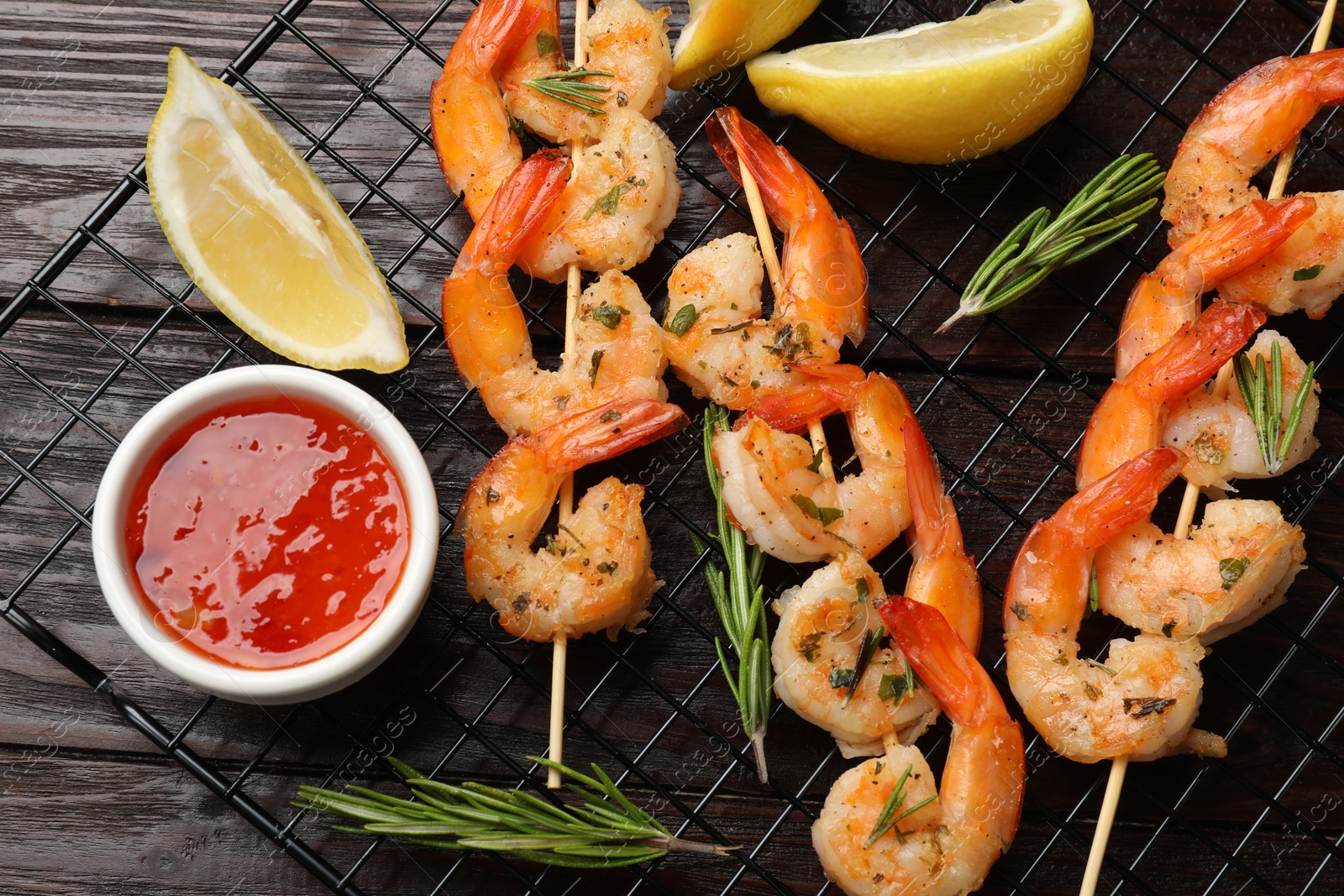 Photo of Skewers with delicious grilled shrimps served on wooden table, flat lay