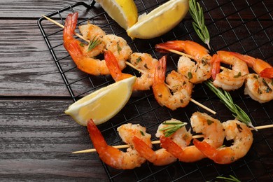 Photo of Skewers with delicious grilled shrimps, herbs and lemon on wooden table, flat lay