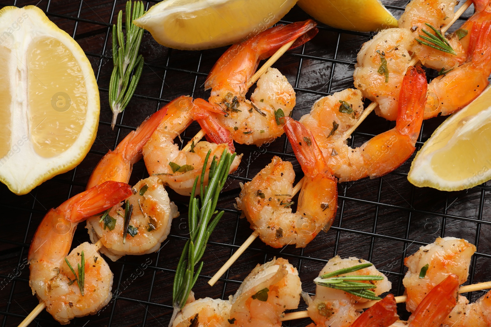 Photo of Skewers with delicious grilled shrimps, herbs and lemon on wooden table, flat lay