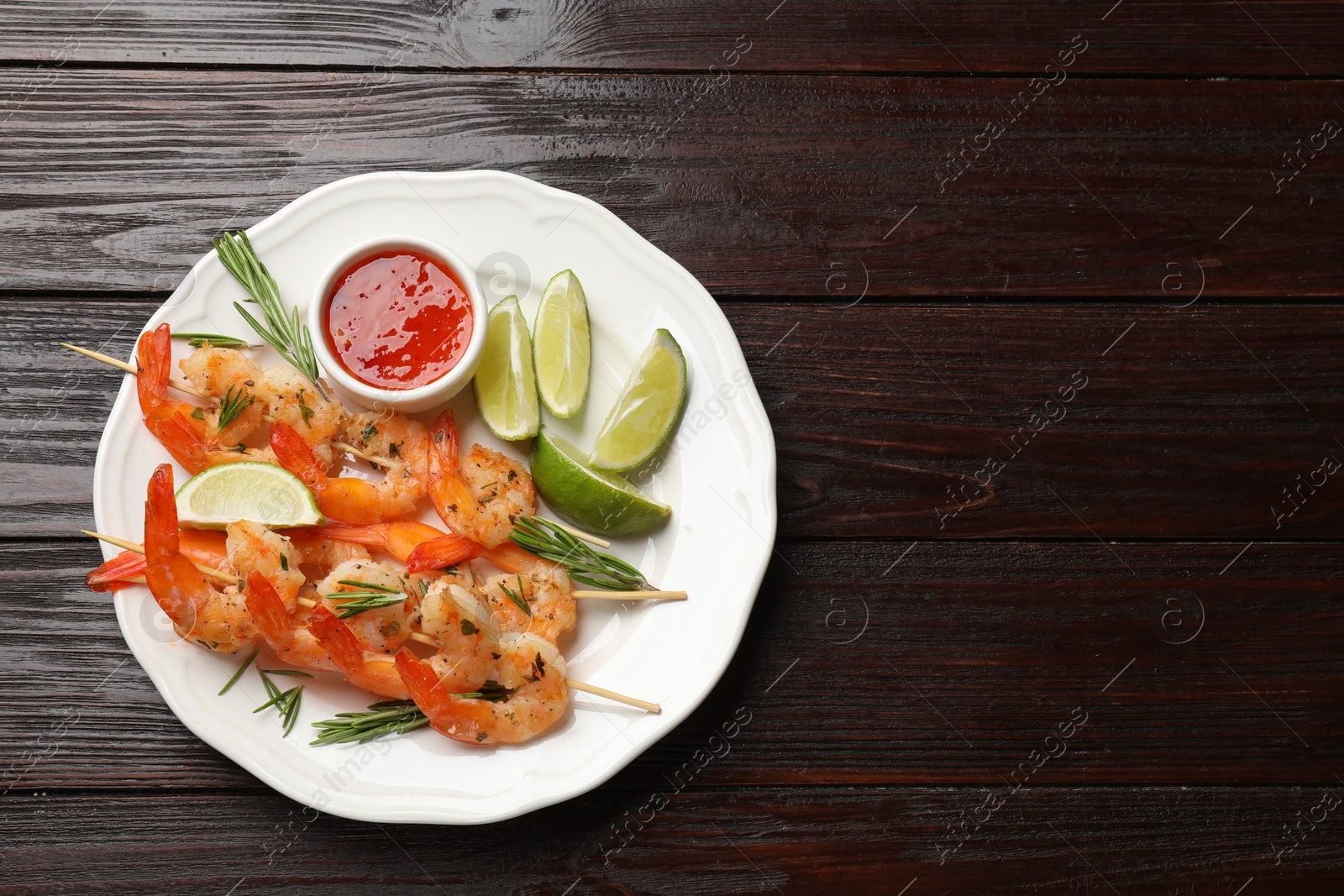 Photo of Skewers with delicious grilled shrimps served on wooden table, top view. Space for text