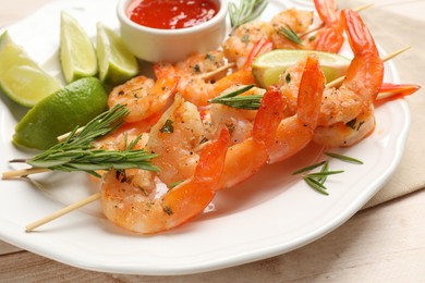 Photo of Skewers with delicious grilled shrimps served on wooden table, closeup