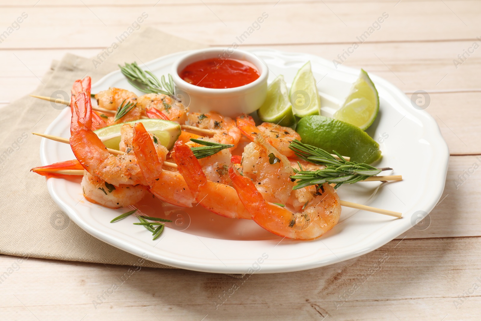 Photo of Skewers with delicious grilled shrimps served on wooden table