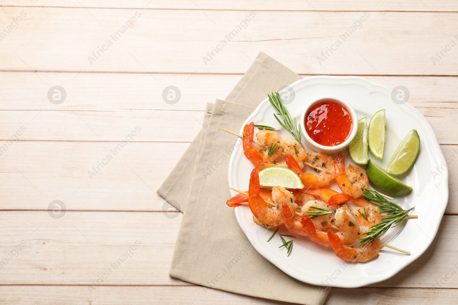 Photo of Skewers with delicious grilled shrimps served on wooden table, top view. Space for text