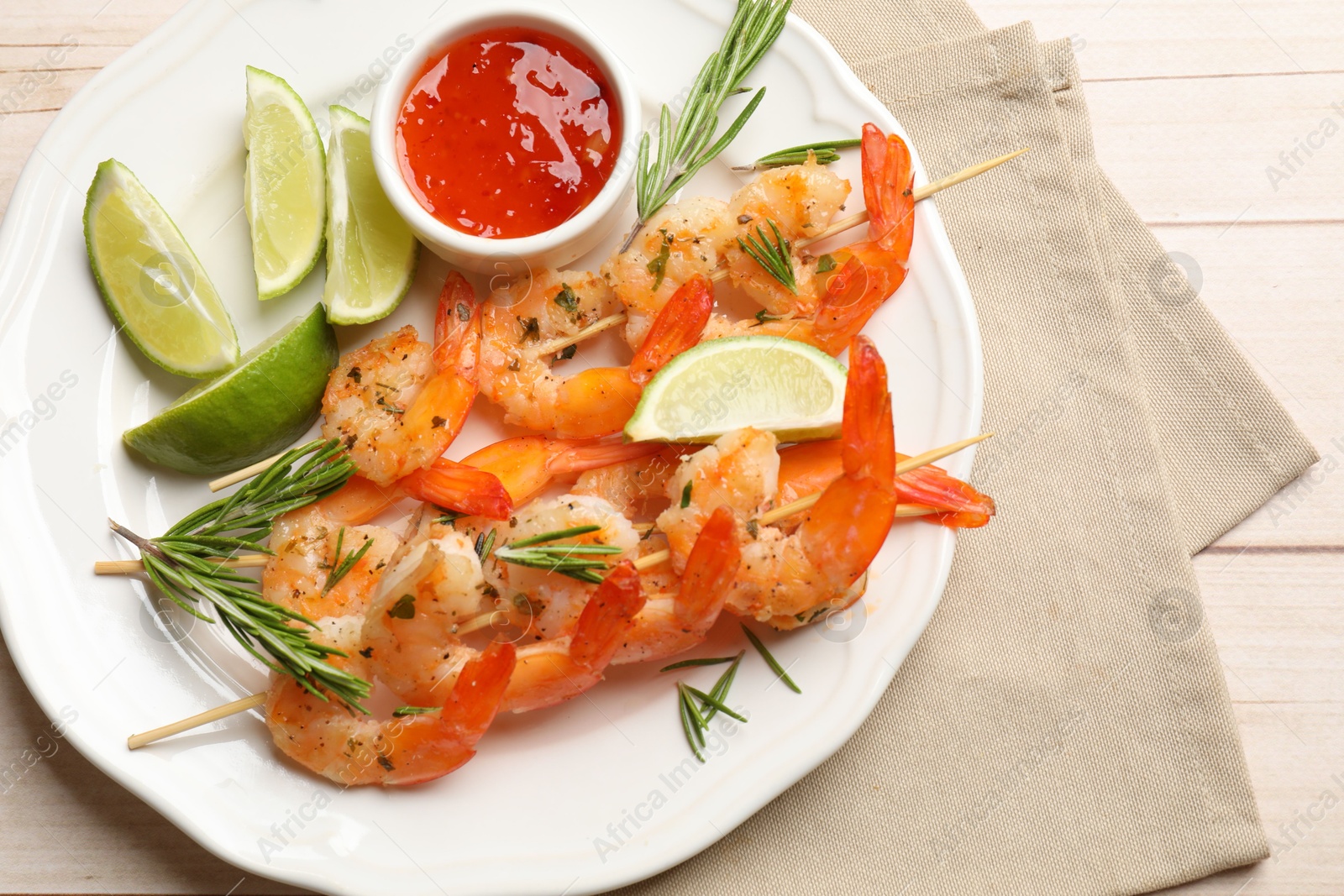 Photo of Skewers with delicious grilled shrimps served on wooden table, top view