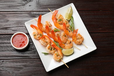 Photo of Skewers with delicious grilled shrimps served on wooden table, flat lay