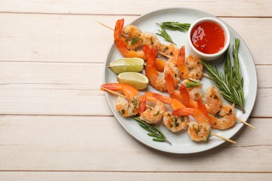 Photo of Skewers with delicious grilled shrimps served on wooden table, top view. Space for text