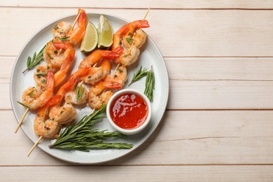 Photo of Skewers with delicious grilled shrimps served on wooden table, top view. Space for text