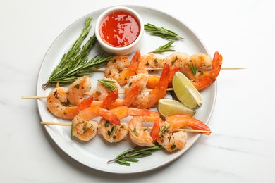 Photo of Skewers with delicious grilled shrimps served on white marble table, top view