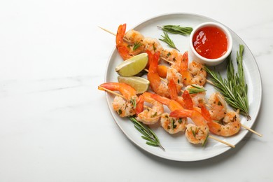 Photo of Skewers with delicious grilled shrimps served on white marble table, top view. Space for text