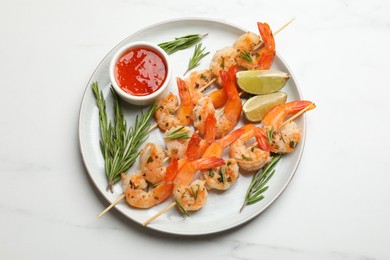 Photo of Skewers with delicious grilled shrimps served on white marble table, top view