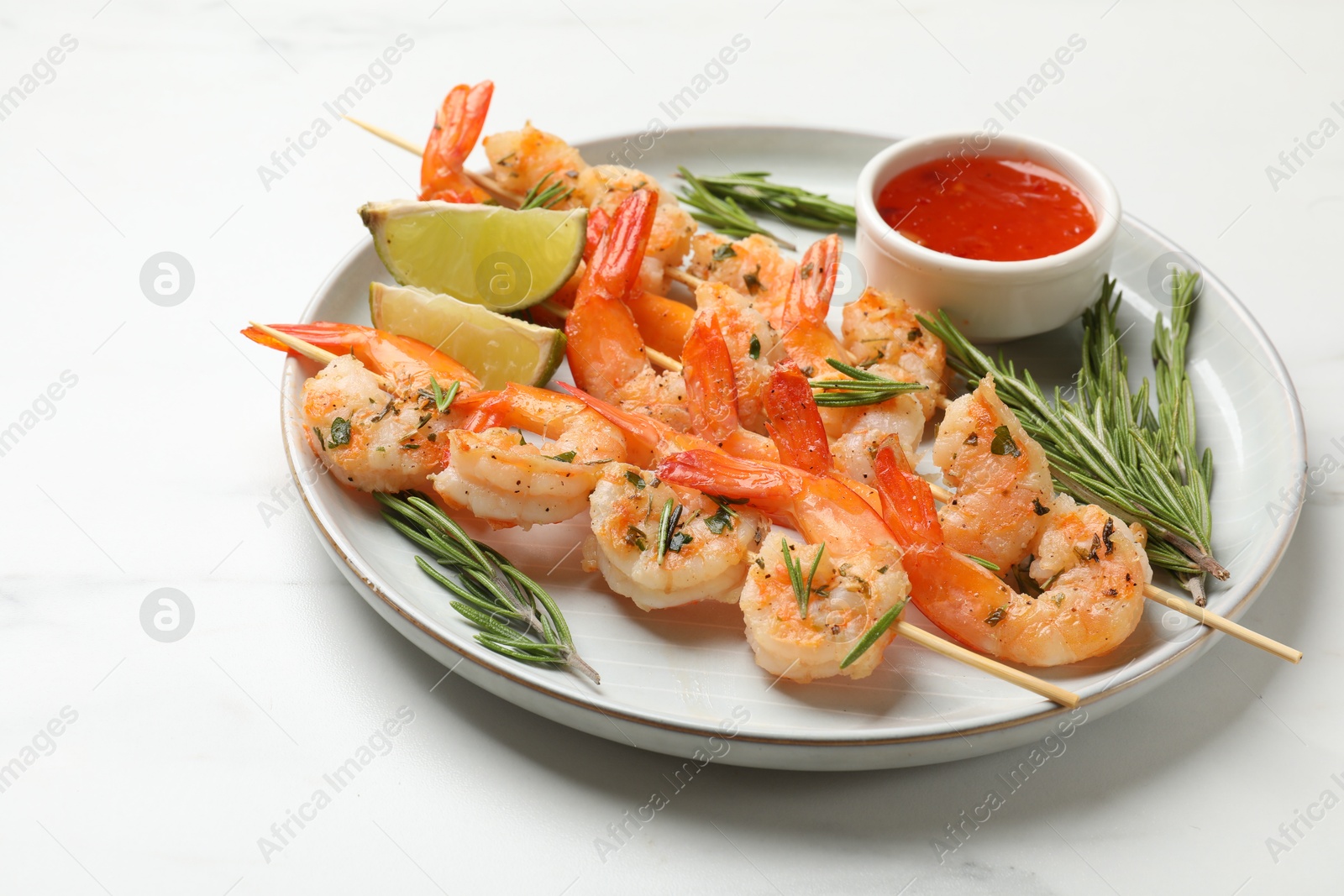 Photo of Skewers with delicious grilled shrimps served on white table