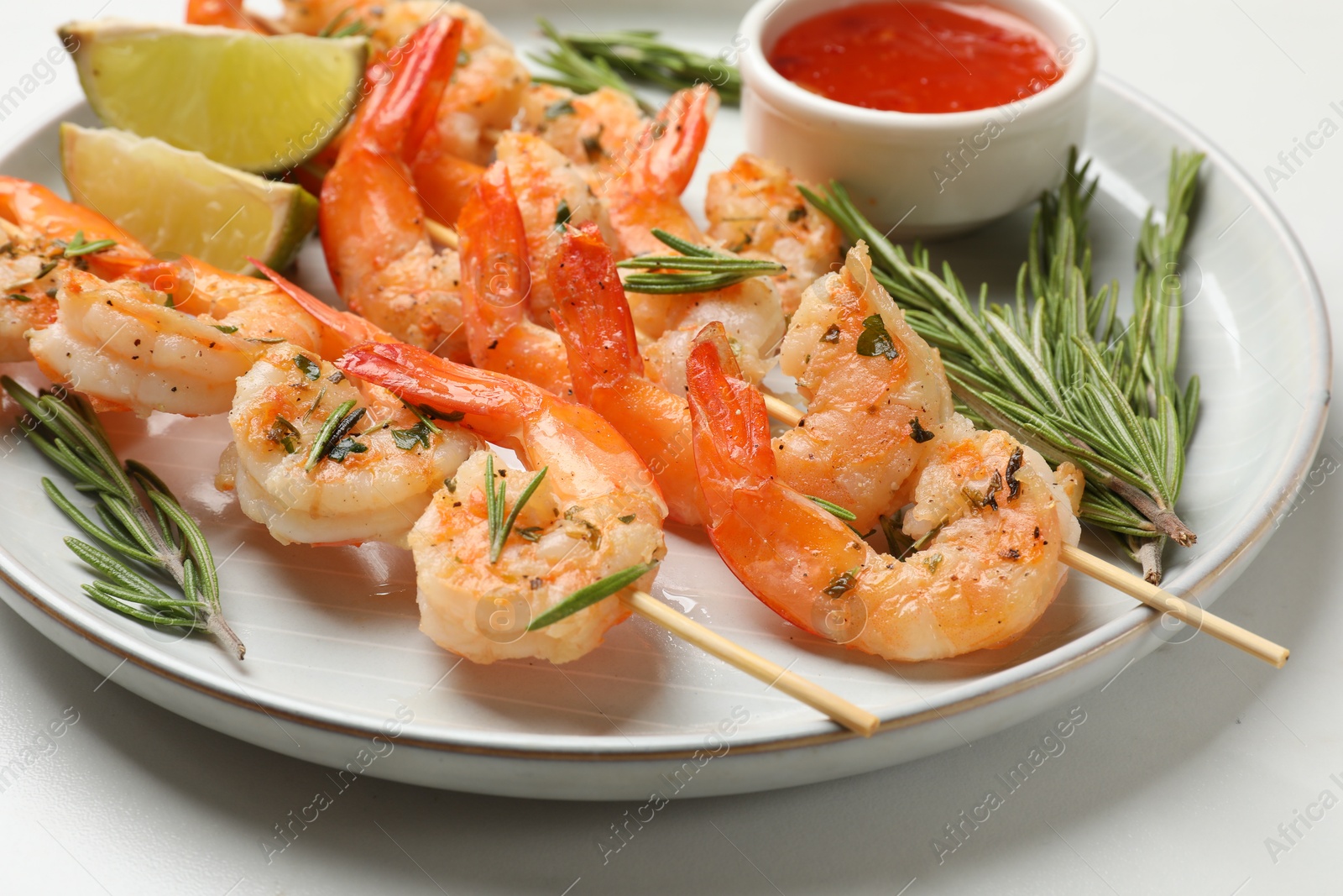 Photo of Skewers with delicious grilled shrimps served on white table, closeup