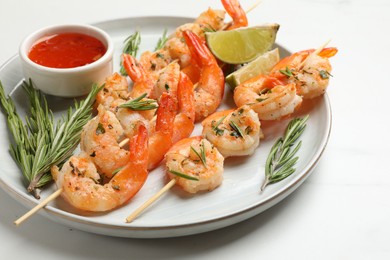 Photo of Skewers with delicious grilled shrimps served on white table, closeup