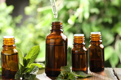 Essential oil dripping from pipette into bottle on table, closeup