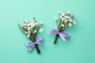 Small stylish boutonnieres on turquoise background, flat lay